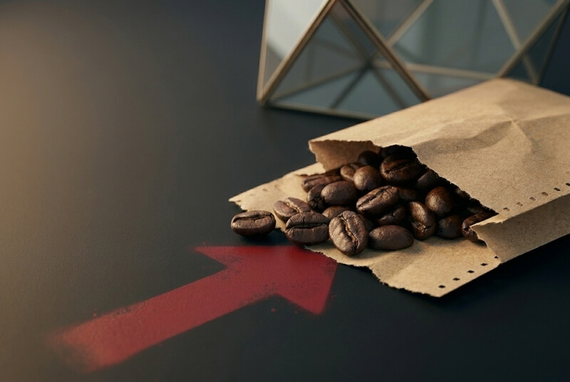 Grãos de café derramando sobre um cupom fiscal rasgado com seta vermelha de alta, ilustrando a inflação do café no Brasil em 2026